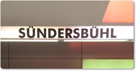 U-Bahn-Magnet Suendersbuehl der Nuernberger Linie U3 in der originalgetreuen Stations-Gestaltung - weisser Streifen mit schwarzer Schrift auf Wandpanelen in dunkelbraun, orange, grau und oliv