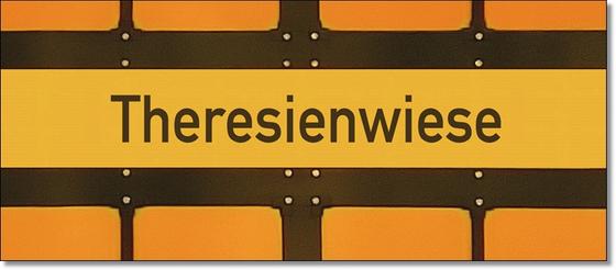 U-Bahnhof Theresienwiese Tasse - schwarze Schrift auf gelbem Schild, vor gelbem Hintergrund mit schwarzen Umrandungen