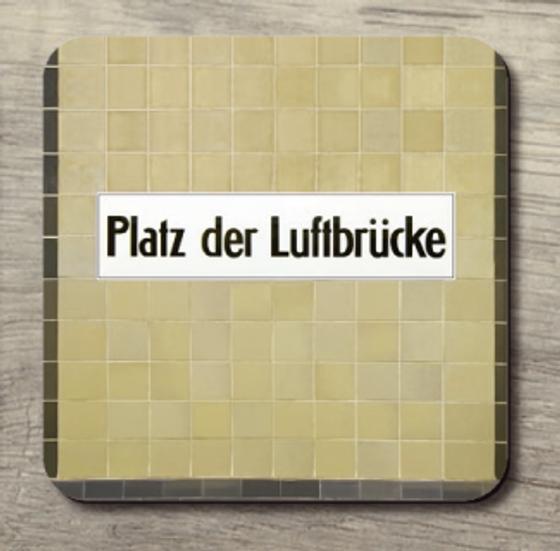 U-Bahnhof Platz der Luftbrücke - schwarze Schrift auf weißem Schild im Hintergrund beige Fliesen; jeweils seitlich waagrecht brauner Fliesenstreifen