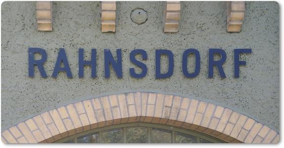 S-Bahnhof Rahnsdorf - dunkelblaue Lettern auf blass-blauer Fassade mit Torbogen aus hellem Backstein
