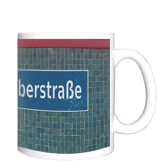 U-Bahnhof Scharnweberstraße Kaffeetasse - weiße Schrift auf dunkelblauem Schild, vor Mosaikwand in verschiedenen Blautönen, unter einem roten Streifen