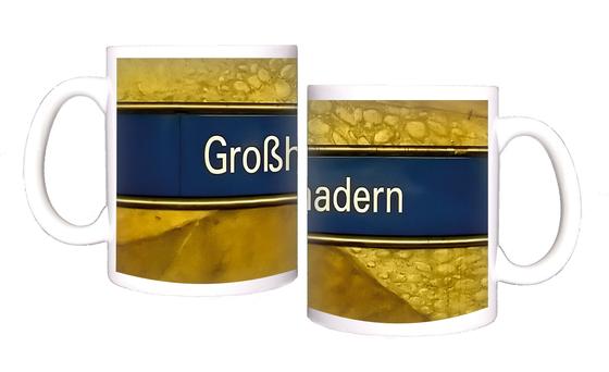U-Bahnhof Großhadern Kaffeetasse - weiße Schrift auf dunkelblauem Streifen, vor gelber Wand mit Steinmuster