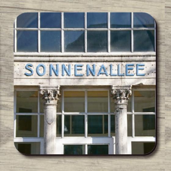 S-Bahnhof Sonnenallee - hellblaue Lettern auf von Säulen gestützten Balken im Hintergrund Fensterfront