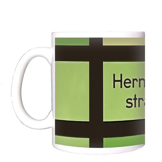 U-Bahnhof Hermannstraße Kaffeetasse - schwarze Schrift vor grün-gelbem Hintergrund mit schwarzem Gittermuster