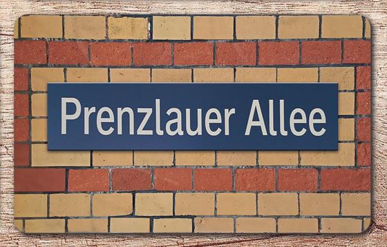 S-Bahnhof Prenzlauer Allee Frühstücksbrettchen  Berlin - blaues Schild mit weißer Schrift auf rot-beigem Backsteinhintergrund