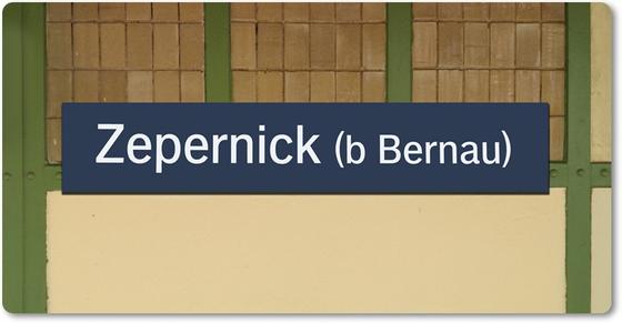 S-Bahn-Kühlschrankmagnet Zepernick bei Bernau - weiße Schrift auf blauem Schild darunter beige Kacheln und darüber rote Backsteine mit grünen Metallvertäfelungen