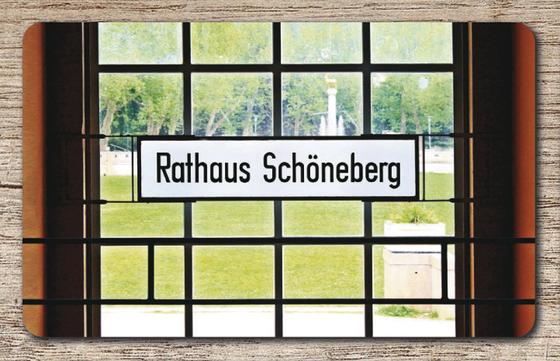 U-Bahnhof Rathaus Schöneberg Frühstücksbrettchen - schwarzer Schrift auf weißem Schild, vor Sprossenfenster