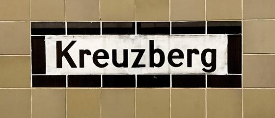 U-Bahnhof Kreuzberg - weißes Schild mit schwarzer Schrift und schwarzem Rand, vor beige-braunen Kacheln