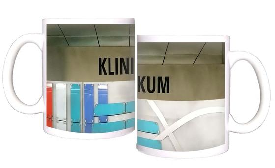 U-Bahn-Tasse Fuerth Klinikum der Nuernberger Linie U1 in der originalgetreuen Stations-Gestaltung - grau-beiges Schild mit schwarzer Schrift, an der Rückwand farbige, brettartige Panelen als Gestaltungselemente