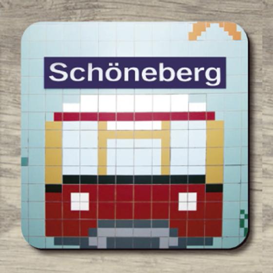 S-Bahnhof Schöneberg - weiße Schrift auf blauem Schild darunter aus Fliesen Ansicht Ende eines Zuges Hintergrund hellblau