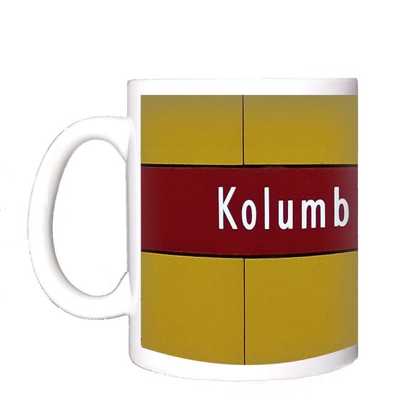 U-Bahnhof Kolumbusplatz Kaffeetasse - weiße Schrift auf dunkelrotem Streifen, vor gelber Plattenwand