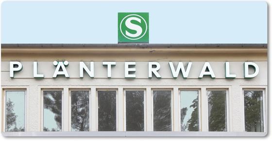S-Bahnhof Plänterwalid Kaffeetasse - weisse Schrift auf beigem Untergrund unter grünem S-Bahn Schild und Himmel