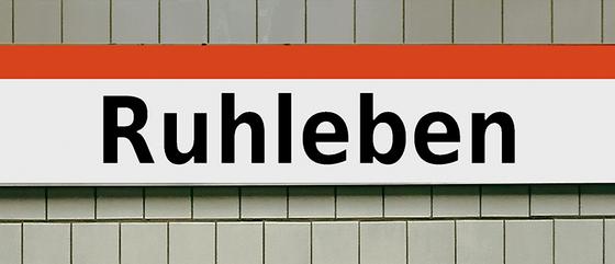 U-Bahnhof Ruhleben Kaffeetasse - schwarze Schrift auf weißem Schild mit orangem Streifen auf weißer Fliesenwand