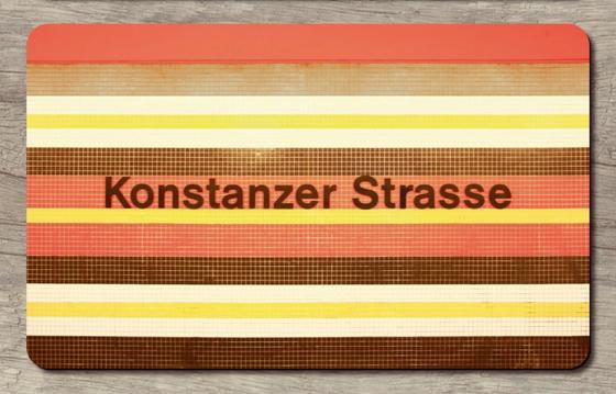 U-Bahnhof Konstanzer Strasse - schwarze Schrift vor orangen, gelben, braun, weißen Fliesenhintergrund