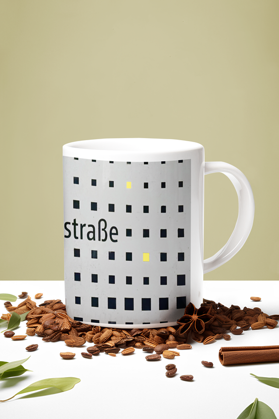 U-Bahnhof Quiddestraße Kaffeetasse - neues Gestaltung seit 2022 - schwarze Schrift auf grauem Grund mit gelb Schwarzen Punkten in unterschiedlicher Größe