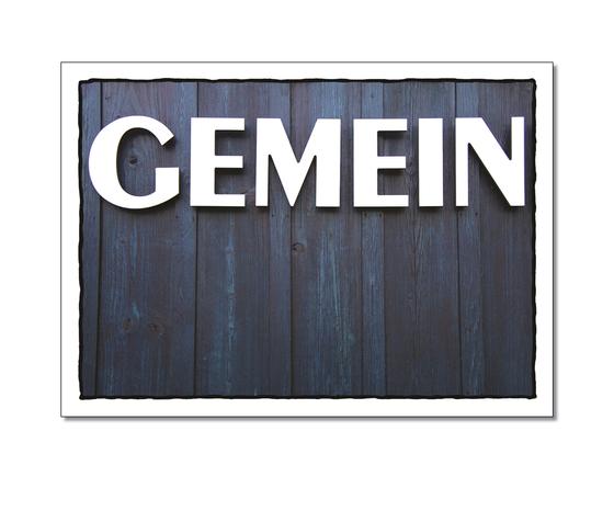 Klassische Postkarte - Boshaft. Foto einer dunklen Holzwand mit der Aufschrift: Gemein. 