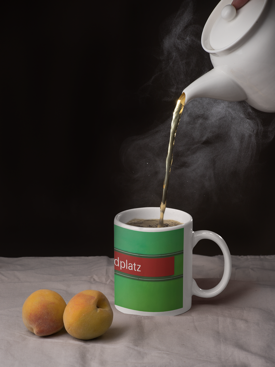 U-Bahnhof Candidplatz Kaffeetasse - weiße Schrift, auf rotem Streifen, schwarz umrandet, vor grünem Untergrund