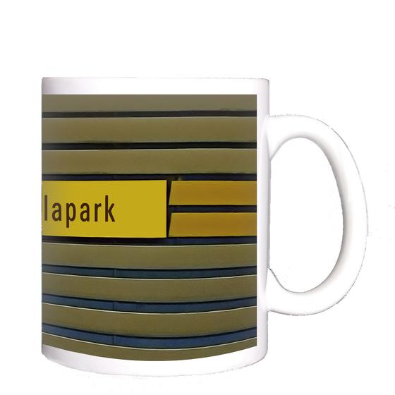 U-Bahnhof Arabellapark Kaffeetasse - schwarze Schrift auf gelbem Streifen, auf blau-braunen Lamellen