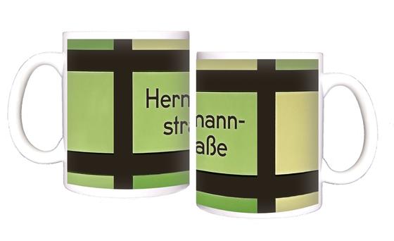 U-Bahnhof Hermannstraße Kaffeetasse - schwarze Schrift vor grün-gelbem Hintergrund mit schwarzem Gittermuster