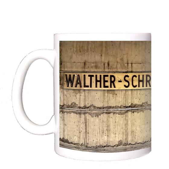 U-Bahnhof Walther-Schreiber-Platz Kaffeetasse - ehemalige Stationsgestaltung, schwarze Schrift auf Messingschild vor grau-brauner Betonwand