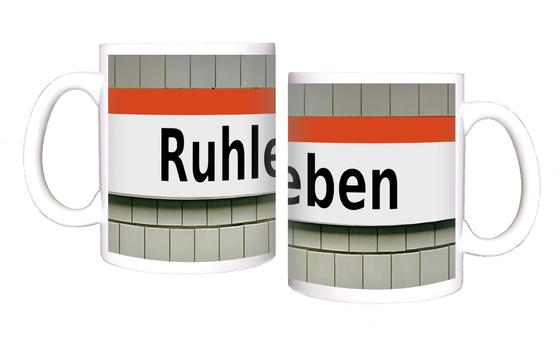 U-Bahnhof Ruhleben Kaffeetasse - schwarze Schrift auf weißem Schild mit orangem Streifen auf weißer Fliesenwand