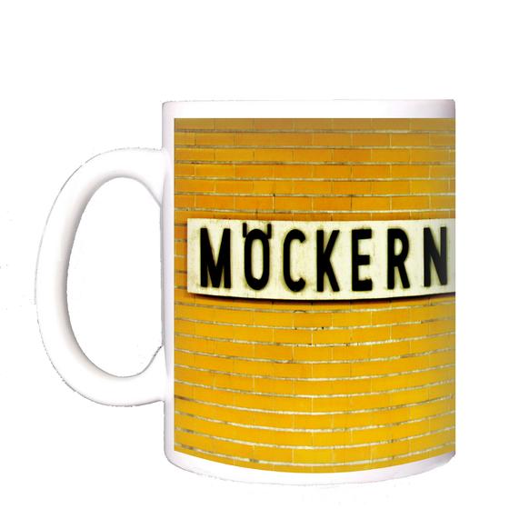U-Bahnhof Möckernbrücke Kaffeetasse - schwarze Schrift auf weißem Schild, vor dunkelgelben Fliesen
