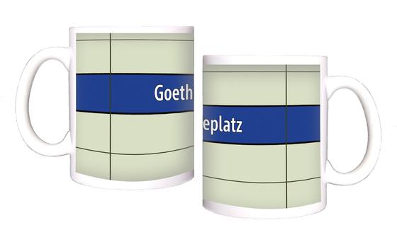 U-Bahnhof Goetheplatz Kaffeetasse - weiße Schrift auf blauem Streifen, vor weißem Plattenhintergrund