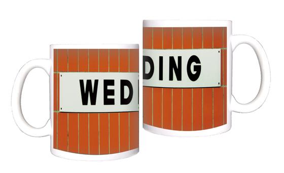 U-Bahnhof Wedding Kaffeetasse - weißes Schild mit schwarzer, schlichter Schrift auf orangen Fliesen