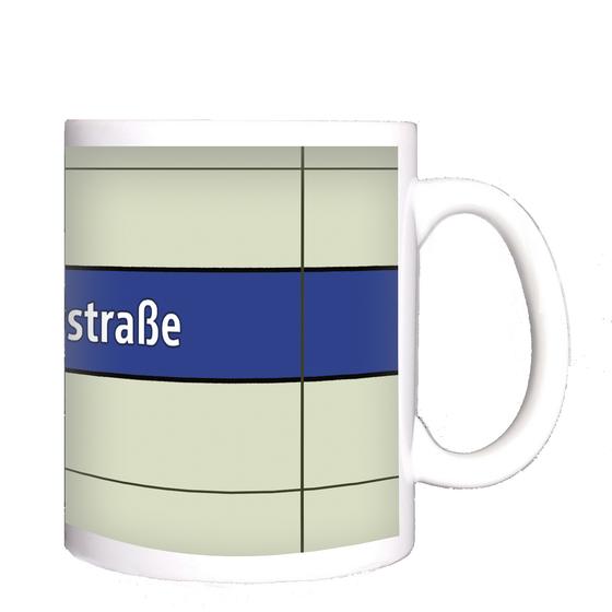 U-Bahnhof Implerstraße Kaffeetasse - weiße Schrift auf blauem Streifen, vor weißem Plattenhintergrund