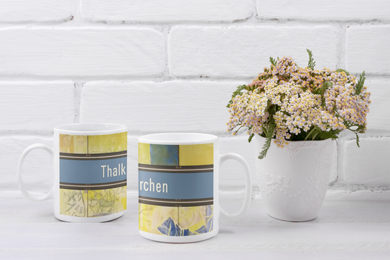 U-Bahnhof Thalkirchen Kaffeetasse - weiße Schrift auf blauem Schild, mit schwarzer Umrandung, auf abstraktem Muster in blau-gelb