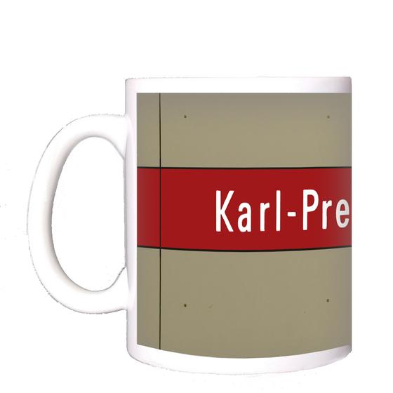 U-Bahnhof Karl-Preis-Platz Kaffeetasse - weiße Schrift auf dunkelrotem Streifen, vor grau-brauner Plattenwand