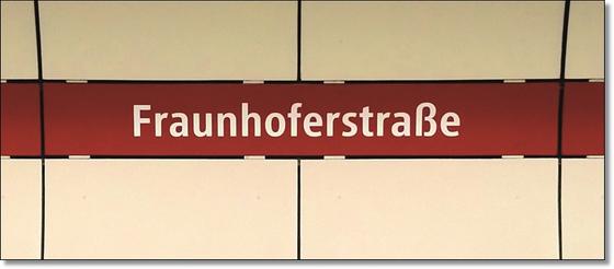U-Bahnhof Fraunhoferstraße Kaffeetasse - weiße Schrift, auf rotem Streifen vor weißer Plattenwand