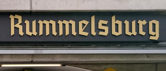 S-Bahnhof Rummelsburg - Frakturschrift in beige auf einem dunklen Schild weitere helle Streifen - Ansicht Tasse links und rechts