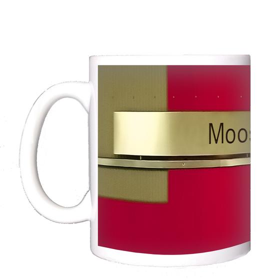 U-Bahnhof Moosfeld Kaffeetasse - schwarze Schrift auf goldenem Schild, vor rotem Untergrund mit grünlichen Elementen