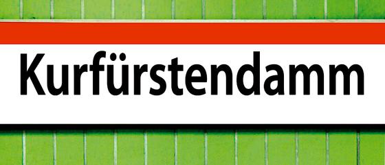 U-Bahnhof Kurfürstendamm Kaffeetasse - weißes Schild mit orangem Streifen und schwarzer Schrift auf grünem Fliesenhintergrund