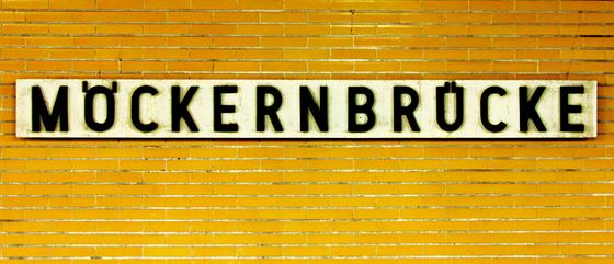 U-Bahnhof Möckernbrücke Kaffeetasse - schwarze Schrift auf weißem Schild, vor dunkelgelben Fliesen