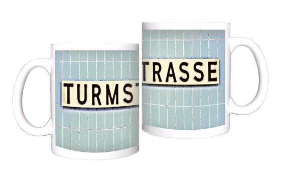 U-Bahnhof Turmstrasse Kaffeetasse - weißes Schild mit schwarzer, schlichter Schrift auf blauen Fliesen
