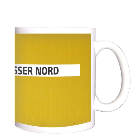 U-Bahn-Tasse Nuernberg Scharfreiterring der Linie U1 in der originalgetreuen Stations-Gestaltung - schwarze Schrift auf weißem Streifen, gelber Streifenbeton Hintergrund