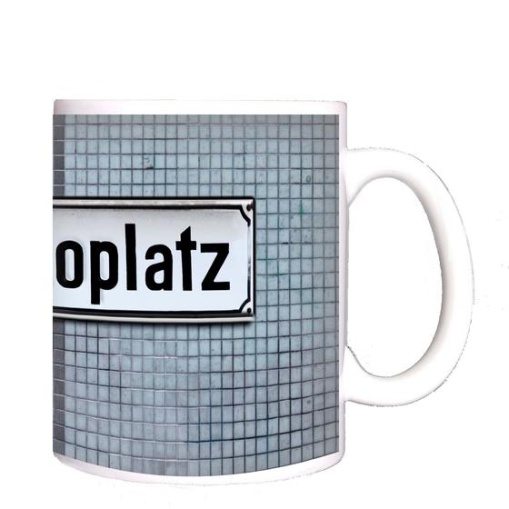 S-Bahnhof Mexikoplatz Kaffeetasse - schwarze Schrift auf weißem Metallschild, vor blauer Mosaikfliesenwand