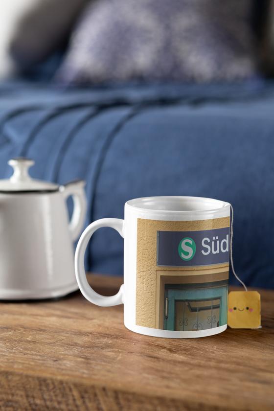 S-Bahnhof Südende S26 Kaffeetasse - weisse Schrift auf blauem Schild über Eingangstür - Umrahmt von beige-brauner Rauputz-Wand
