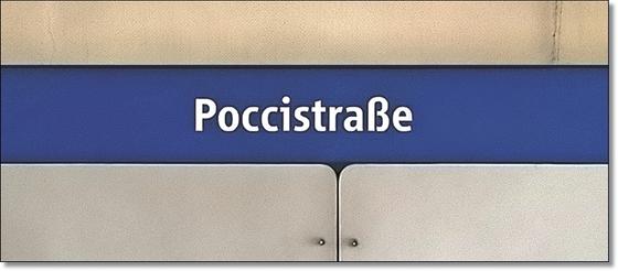 U-Bahnhof Poccistraße Kaffeetasse - weiße Schrift auf dunkelblauem Streifen, vor weißer Plattenwand