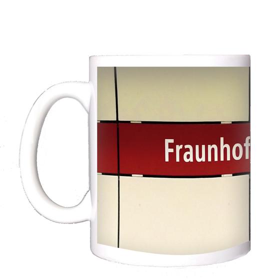 U-Bahnhof Fraunhoferstraße Kaffeetasse - weiße Schrift, auf rotem Streifen vor weißer Plattenwand