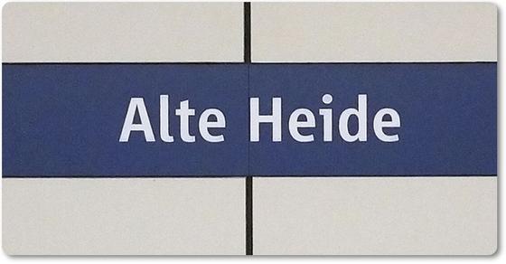 U-Bahnhof Alte Heide - weiße Schrift auf lila-blauem Streifen vor weißem Hintergrund