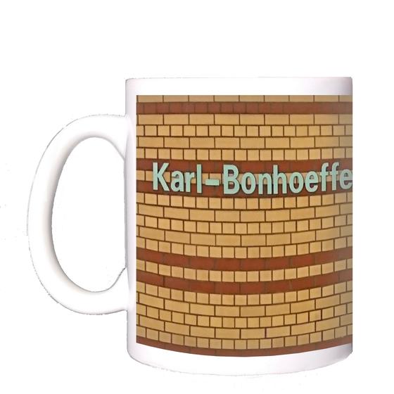 U-Bahnhof Karl-Bonhoeffer-Nervenklinik Kaffeetasse - weiße Lettern auf gelbem Backsteinhintergrund mit rötlich-braunen Streifen
