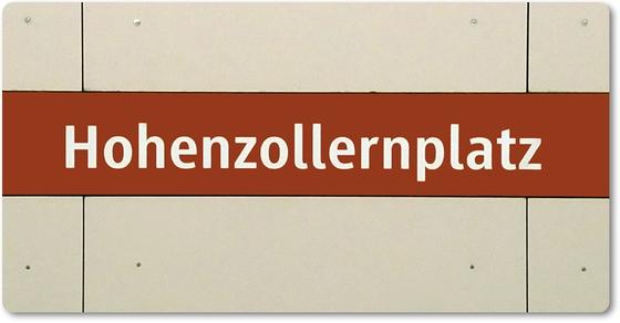 Kühlschrankmagnet bedruckt mit dem Bahnhofsschild des Muenchner U-Bahnhofs Hohenzollernplatz im Ortsteil Schwabing-West. Weisse Schrift auf rotem Streifen auf hellgrauen Wandpanelen