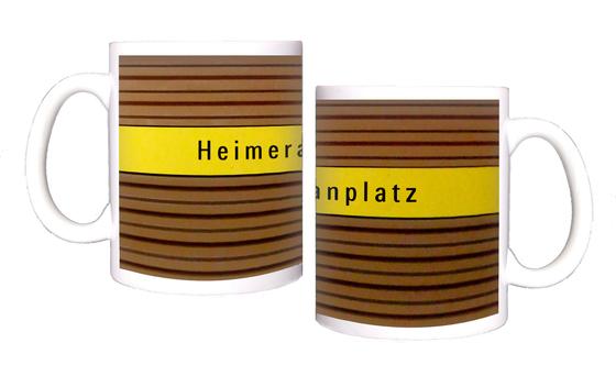 U-Bahnhof Heimeranplatz Kaffeetasse - schwarze Schrift auf gelbem Streifen, vor braunem Riffelhintergrund