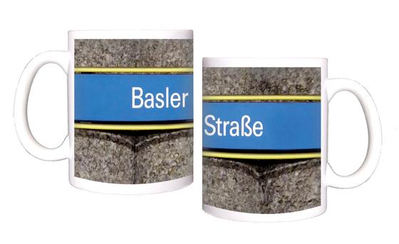 U-Bahnhof Basler Straße Kaffeetasse - weiße Schrift auf hellblauem Schild, gelb umrandet, vor grauer Säulenwand