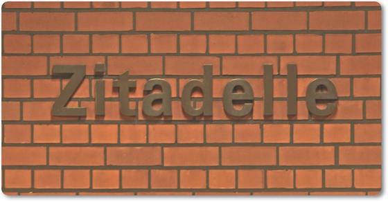 U-Bahnhof Zitadelle - dunkelbraune Lettern vor roter Backsteinmauer