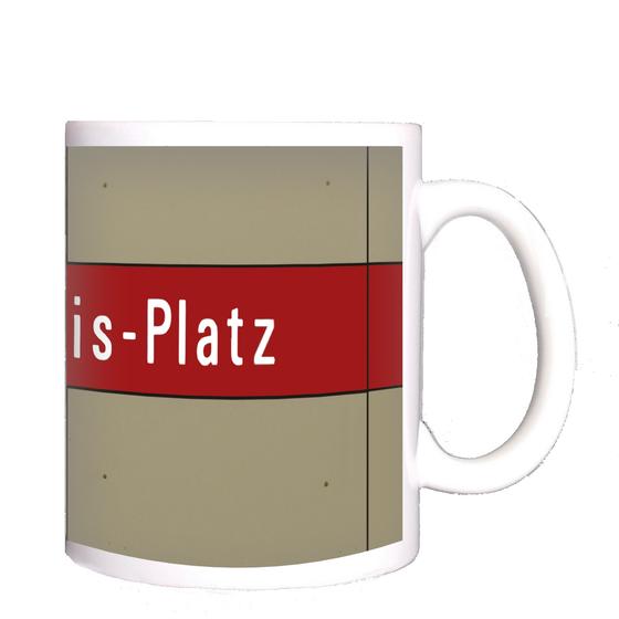 U-Bahnhof Karl-Preis-Platz Kaffeetasse - weiße Schrift auf dunkelrotem Streifen, vor grau-brauner Plattenwand