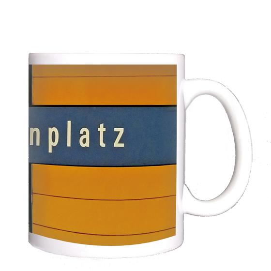 U-Bahnhof Marienplatz Kaffeetasse - weiße Schrift auf blauem Schild, vor orangem Hintergrund